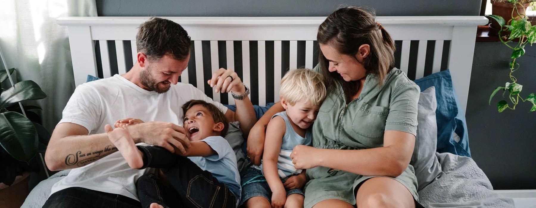 parents play with their children on a bed